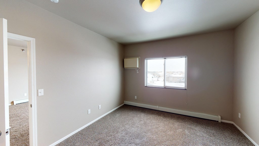 A room with a window and carpeted floor.