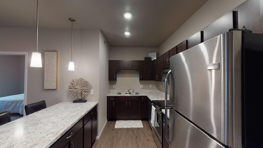 A modern kitchen with a large refrigerator and wooden cabinets.