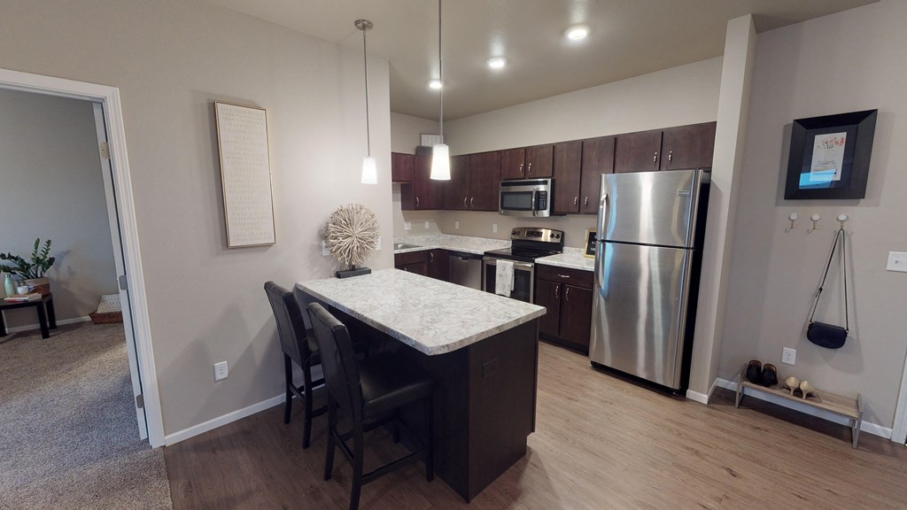 A kitchen with a table and chairs in front of a refrigerator.