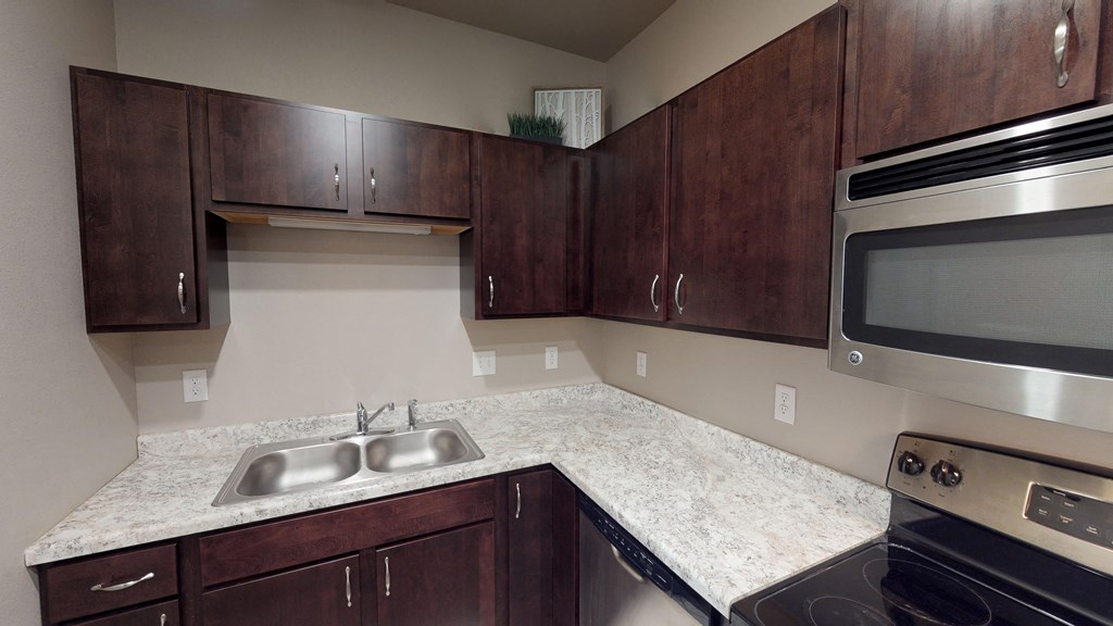 A kitchen with dark wood cabinets and stainless steel appliances.