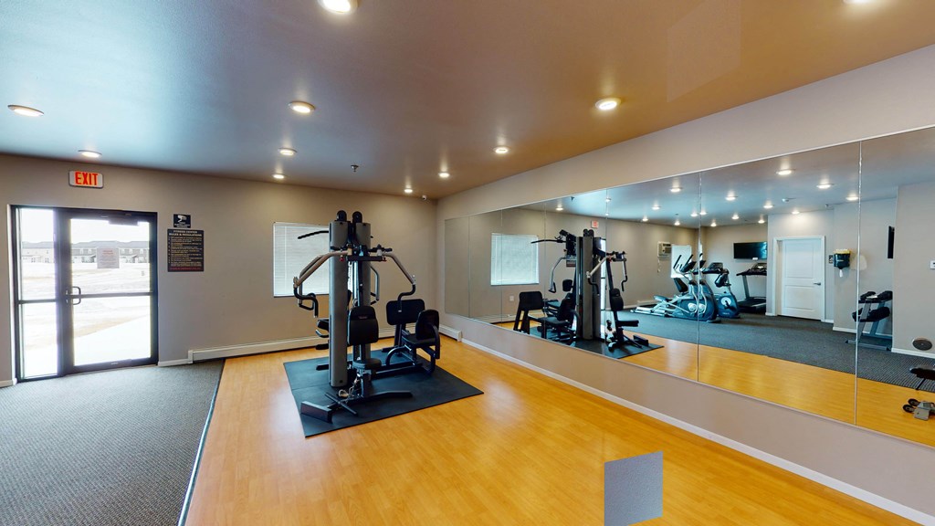 A gym with a mirrored wall and a variety of equipment.