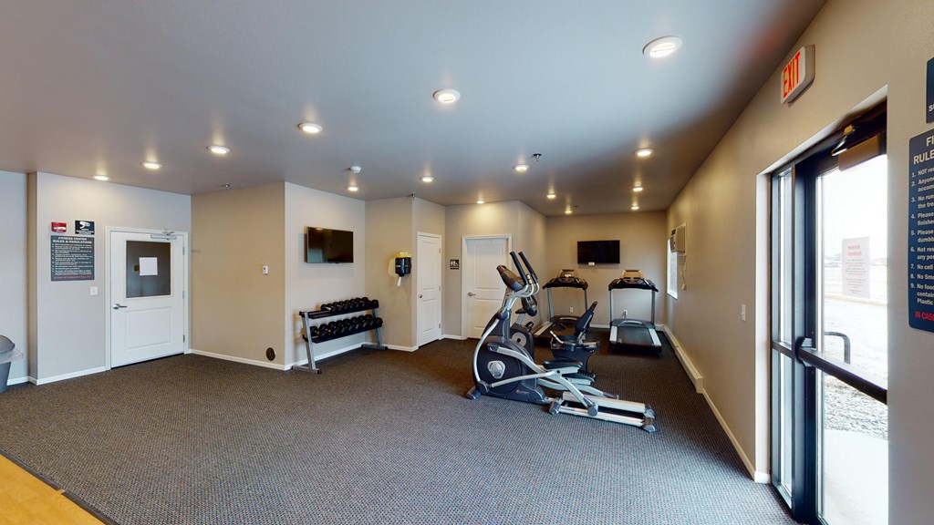 A gym with a variety of equipment including a treadmill, exercise bike, and weight bench.