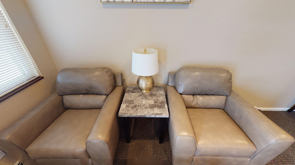 A grey leather sofa with a marble table in front of it.