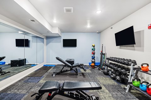A gym with a variety of equipment including weights and exercise machines.
