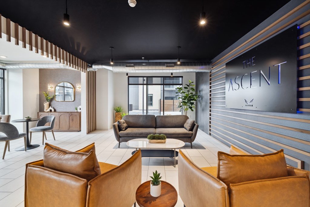 A modern living room with brown leather chairs and a sign that reads "The Ascent".