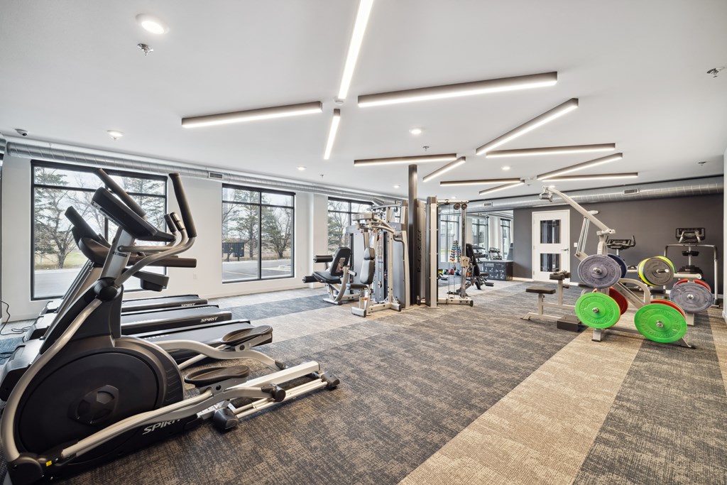 A gym with a variety of equipment including treadmills, weights, and exercise machines.