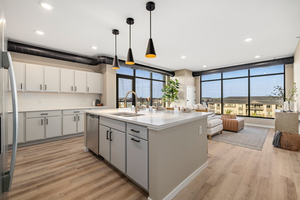 A modern kitchen with a large island and pendant lights.