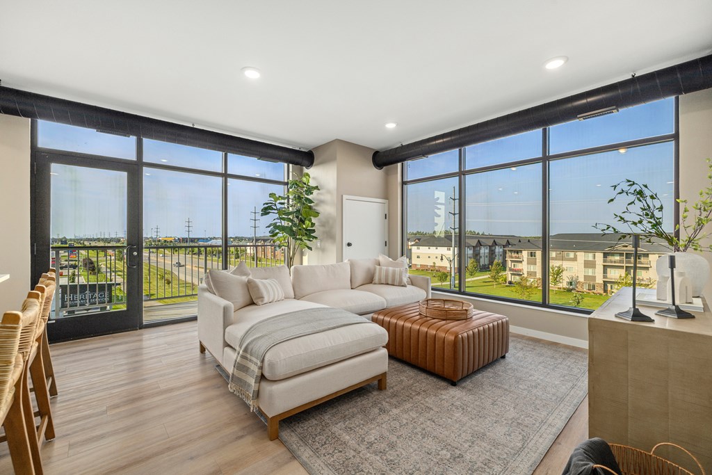 A living room with a couch, a chair, and a large window overlooking a balcony.