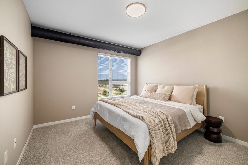 A bedroom with a large bed and a window overlooking the ocean.