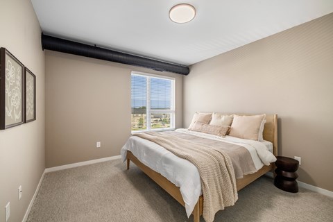 A bedroom with a large bed and a window overlooking the ocean.