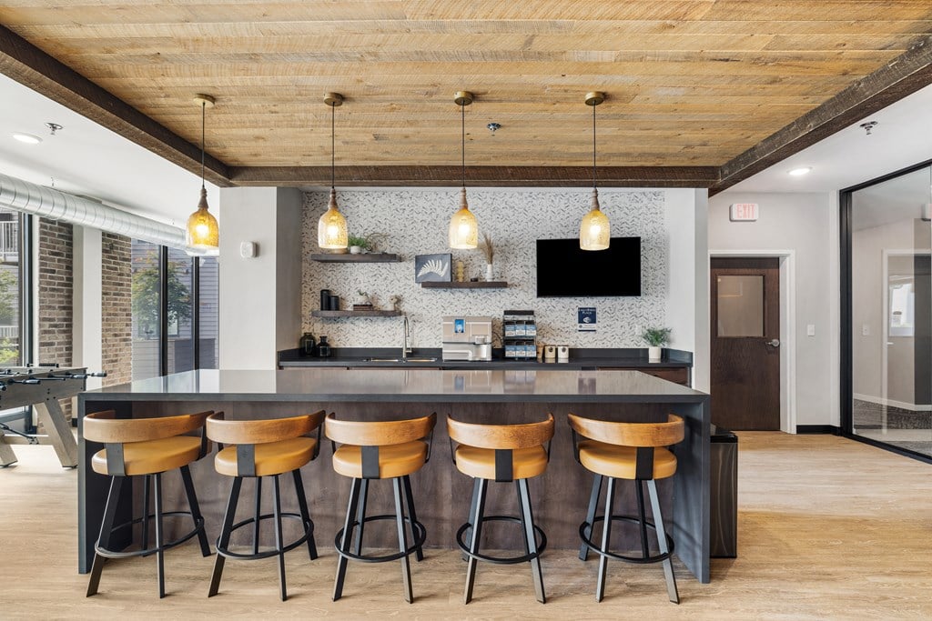 a kitchen with a large island with four stools and a tv on the wall at EagleRidge Plaza Residences, North Dakota
