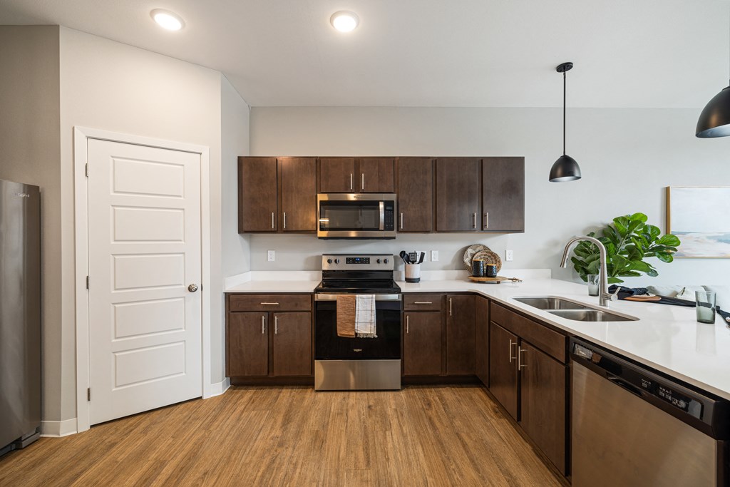a kitchen with wooden cabinets and stainless steel appliances and a door at EagleRidge Plaza Residences, Fargo, North Dakota