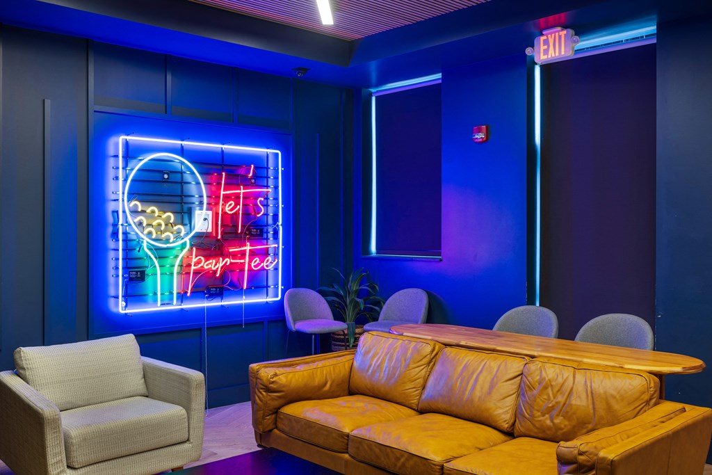 a room with a couch and chairs and a neon sign at EagleRidge Plaza Residences, Fargo, ND