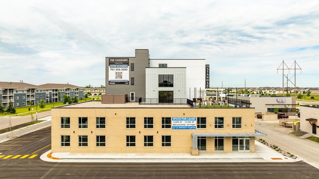 a large building with a sign on top of it in a parking lot at The Standard on 32nd, West Fargo, North Dakota