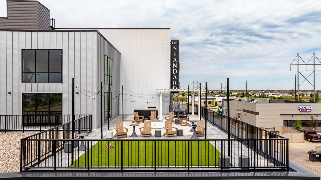 a large white building with a patio with tables and chairs at The Standard on 32nd, West Fargo