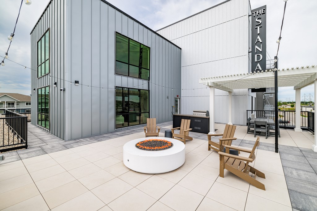 a patio with a fire pit and chairs outside of a building at The Standard on 32nd, West Fargo, ND