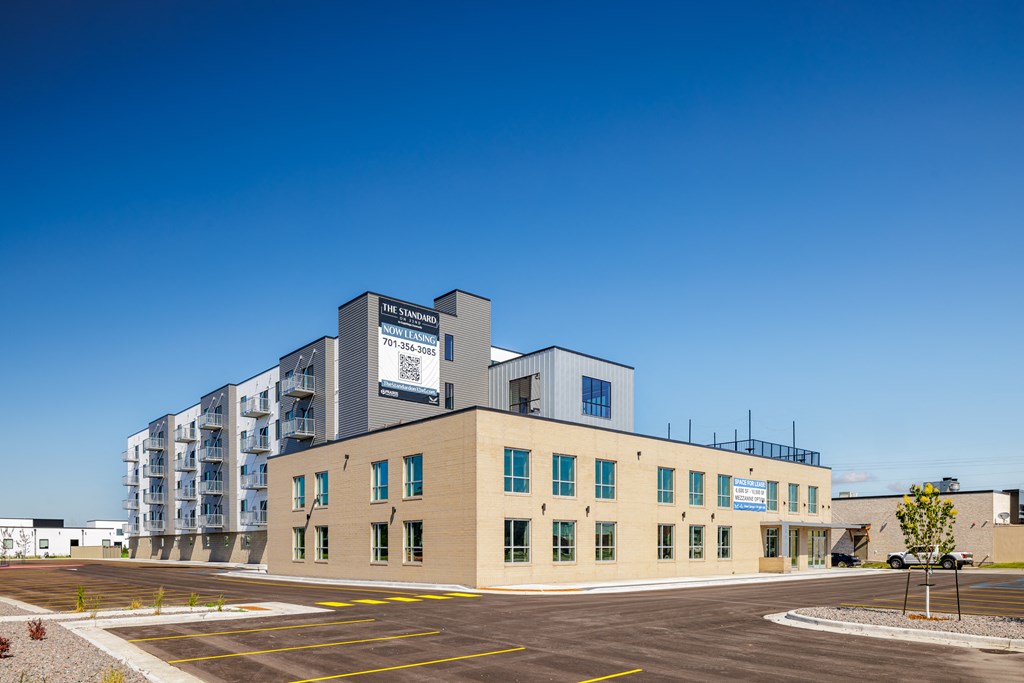 a building with a parking lot and a blue sky at The Standard on 32nd, West Fargo