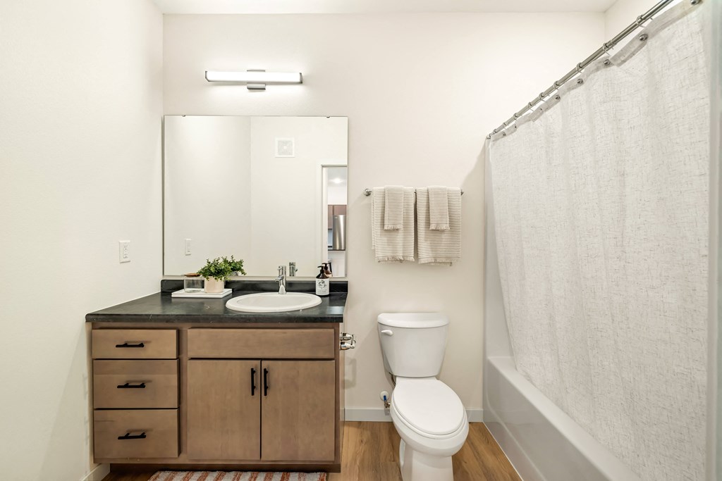 a bathroom with a toilet sink and mirror and a shower at The Standard on 32nd, West Fargo, ND