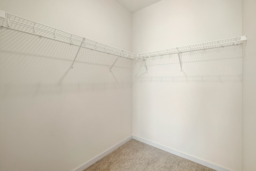 a spacious closet with white walls and shelves and a carpeted floor a spacious closet with white walls and shelves and a carpeted floor at The Standard on 32nd, West Fargo, North Dakota