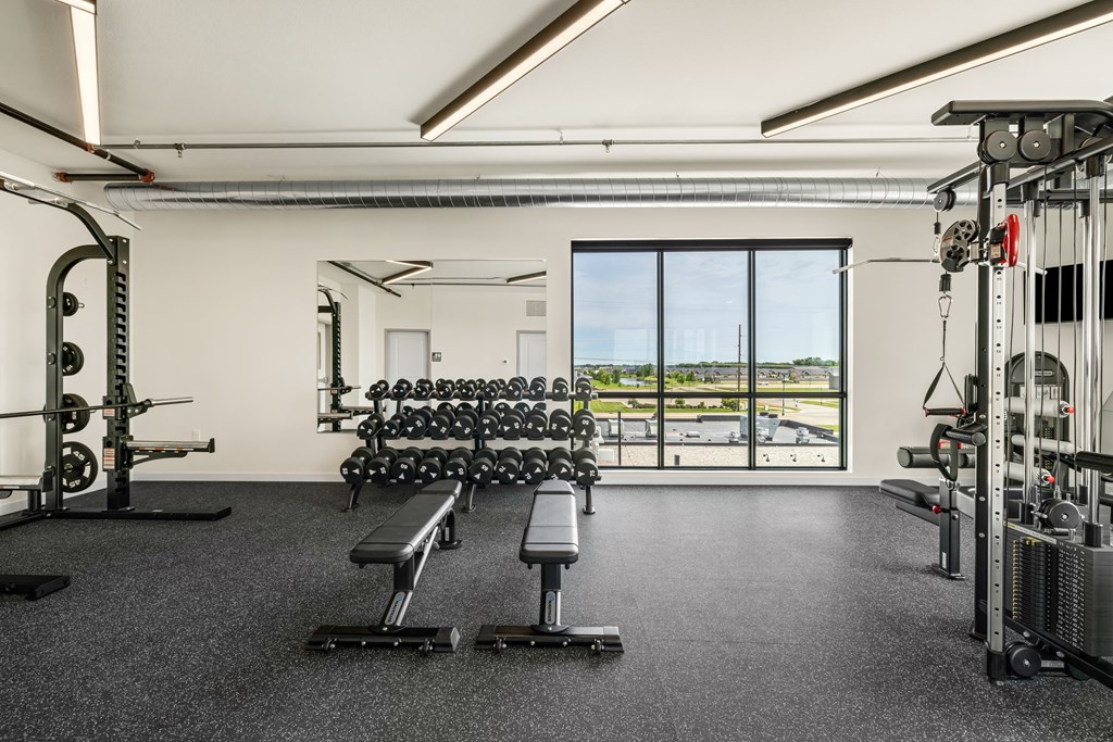a gym with weights machines and a view of a window at The Standard on 32nd, North Dakota