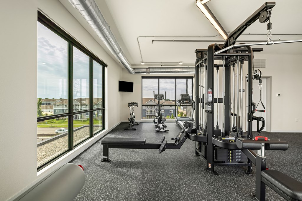 a gym with exercise equipment and windows with a view of a train at The Standard on 32nd, West Fargo, 58078