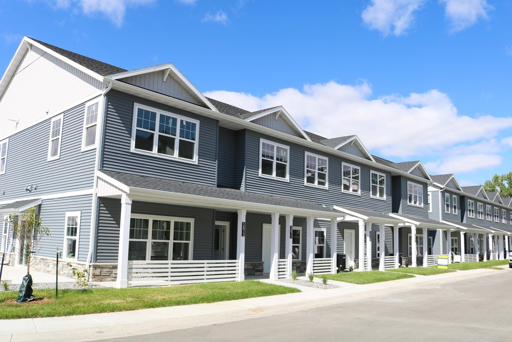 A row of houses with grey siding and white trim.