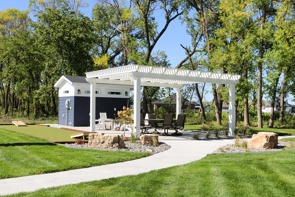 A white gazebo is surrounded by a grassy area and trees.