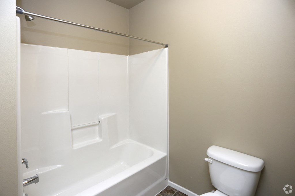 A white bathroom with a toilet and a walk in shower.