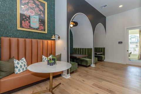 A living room with a round table and a couch with a green cushion.