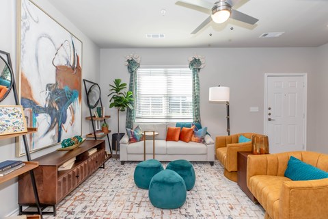 A living room with a white couch, a brown chair, and a painting on the wall.