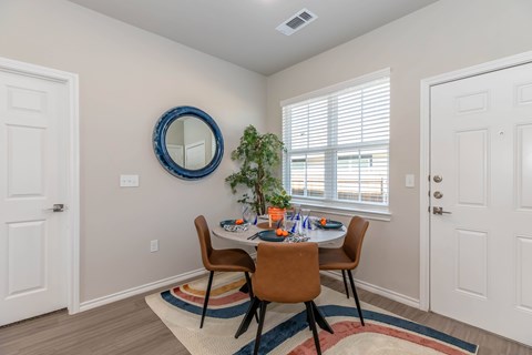 A dining room with a round mirror and a table with chairs.