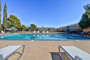 a swimming pool with two picnic tables in front of a building