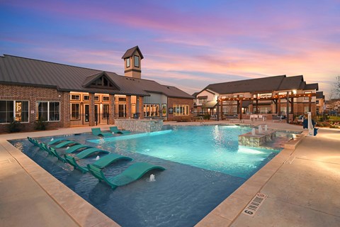 a swimming pool with lounge chairs in front of a building