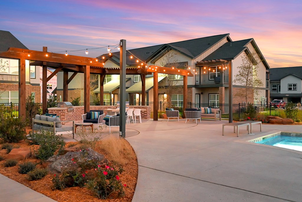 an outdoor patio with chairs and a pool at dusk