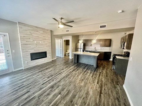 an empty living room with a fireplace and a kitchen