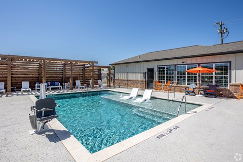A pool with chairs around it and a building in the background.
