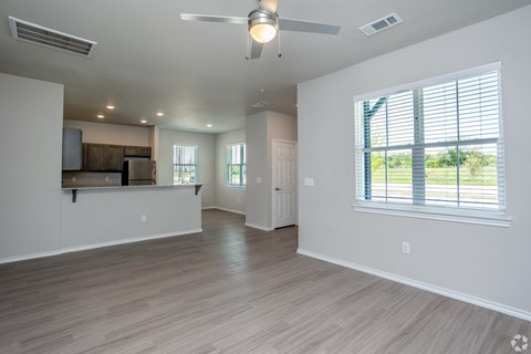 A spacious room with a ceiling fan and a window with blinds.