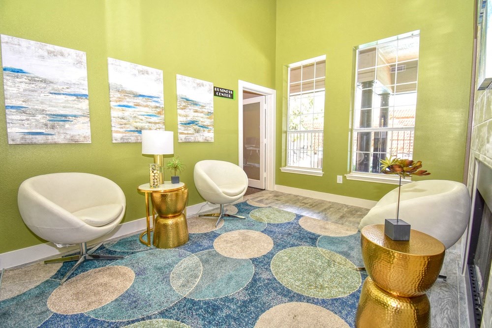a living room with green walls and chairs and a rug