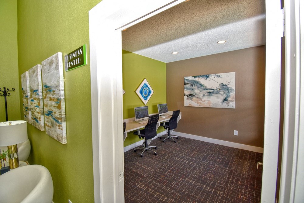 a room with a desk with two computers and a toilet
