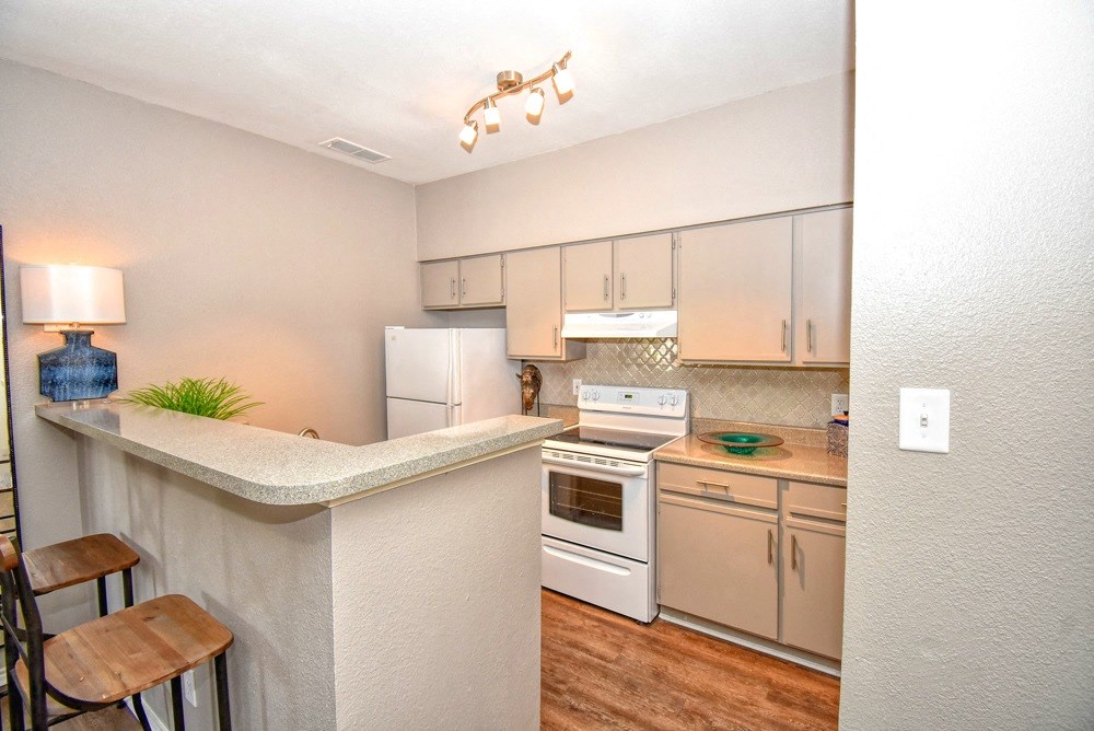 a kitchen with white appliances and a bar with stools