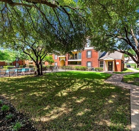 a yard with trees and a brick building