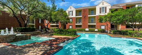 a swimming pool with a fountain in front of an apartment building