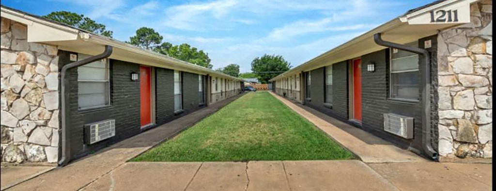 a row of buildings with closed doors and a grass sidewalk