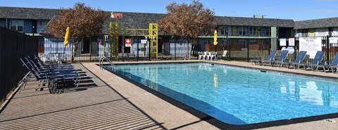 A large outdoor swimming pool surrounded by a wooden deck and lounge chairs.