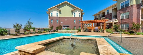 A large outdoor swimming pool with a fountain in the middle of it.