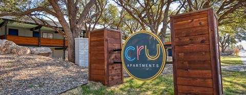 A sign for Cru Apartments stands in front of a building.