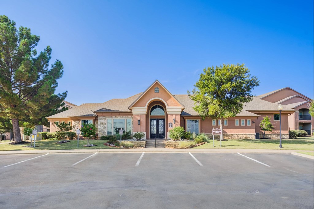 A building with a black door and windows surrounded by a parking lot.
