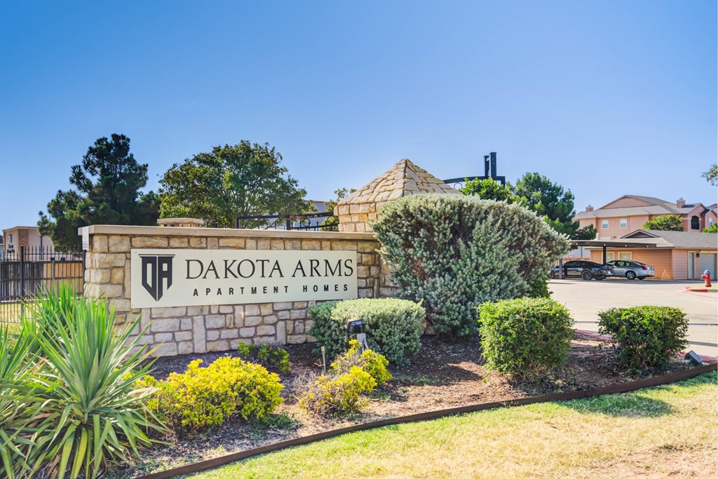 A sign for Dakota Arms Apartment Homes is surrounded by landscaping.