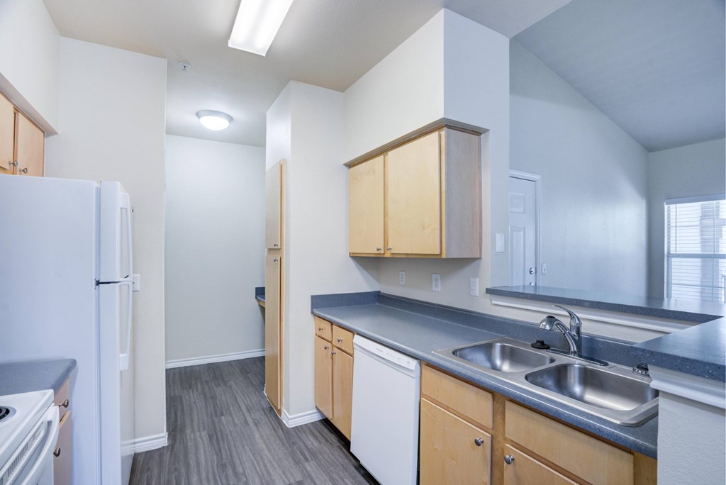 A kitchen with a white refrigerator, wooden cabinets, and a grey countertop.