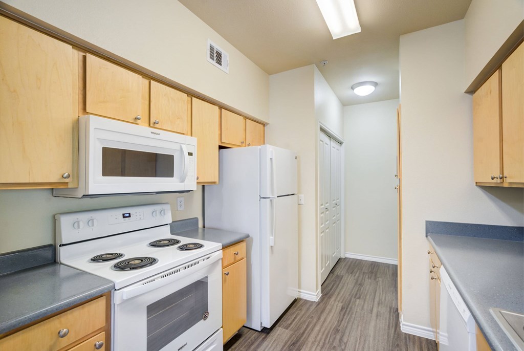 A kitchen with white appliances and wooden cabinets.